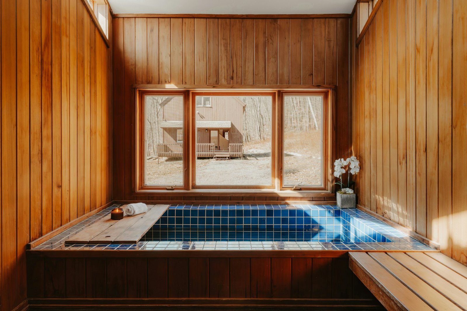 Bain à remous encastré dans un habillage de bois et de mosaïque sombre.
