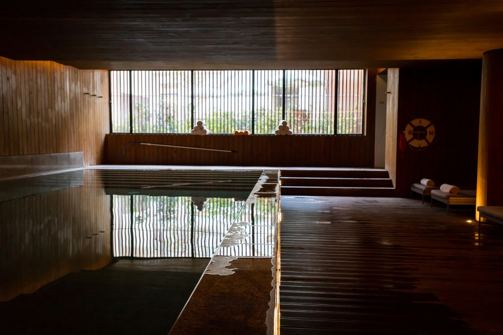 Reflets sur l'eau d'un bassin intérieur aux tons sombres.
