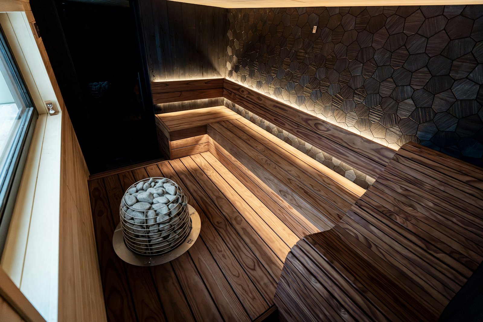 Poêle de sauna garni de pierres, au centre d'une pièce en bois.